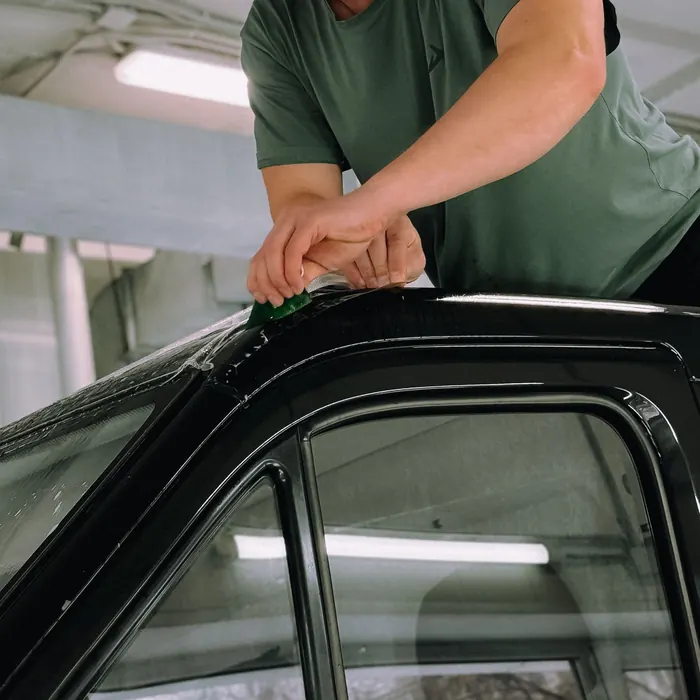 Technician fitting film to a car's door glass