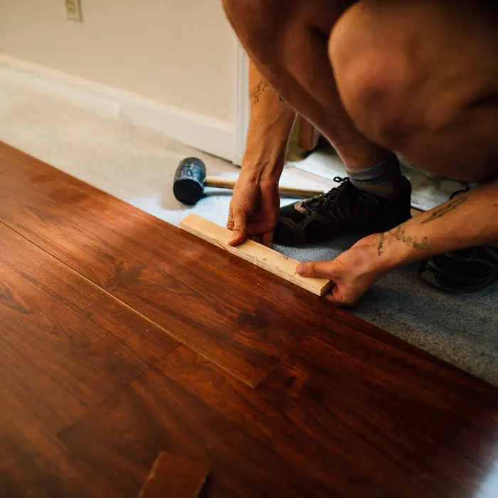 Installer tapping plank flooring into place