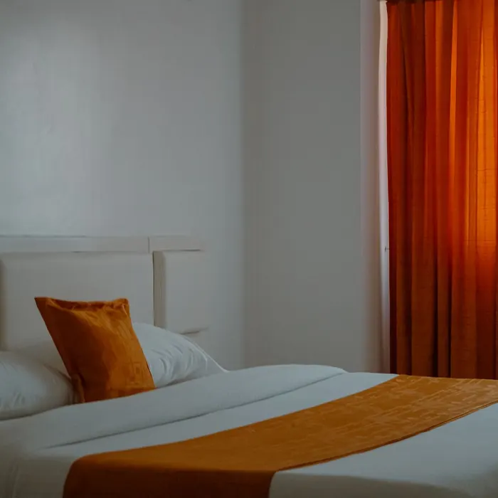 Hotel bed beside a curtained window