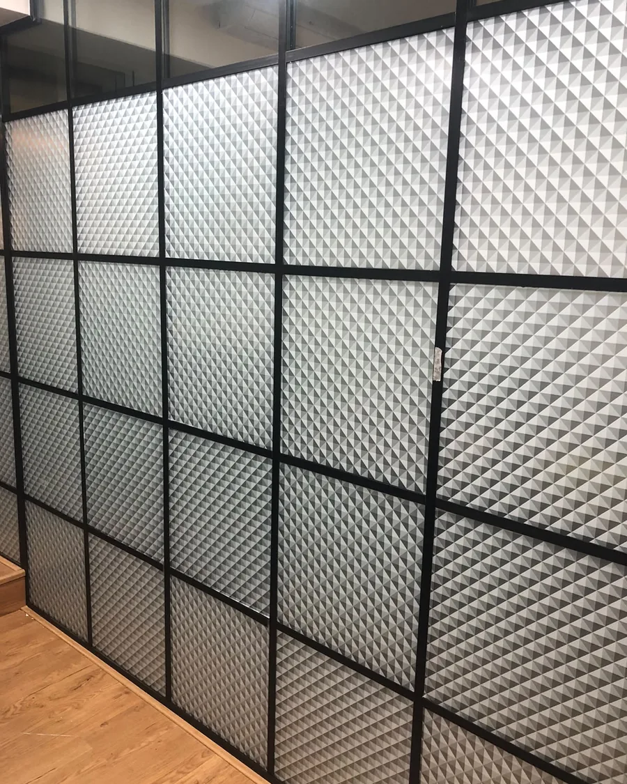 Textured glass panels set into a black grid partition, installed floor to ceiling