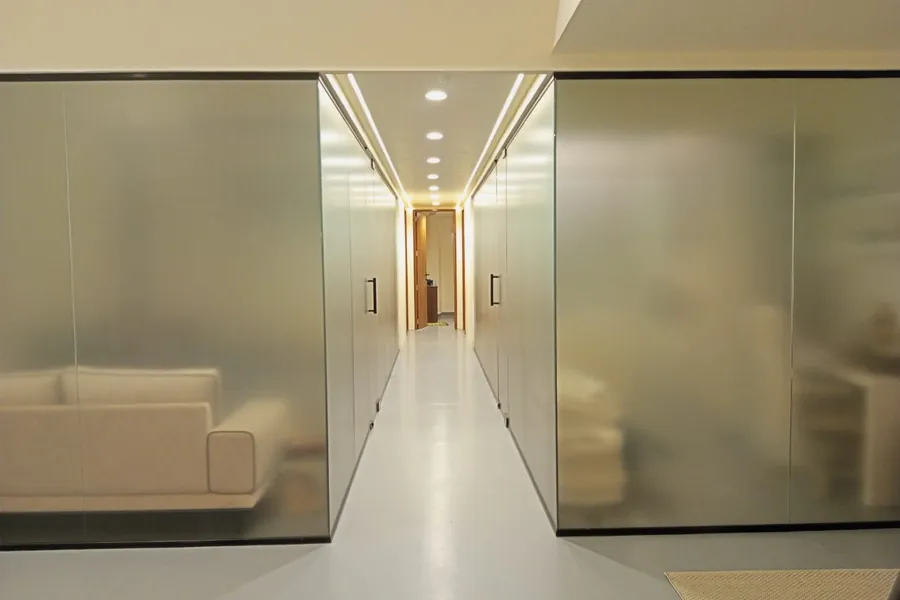 Frosted glass cabin partitions running the length of an office corridor